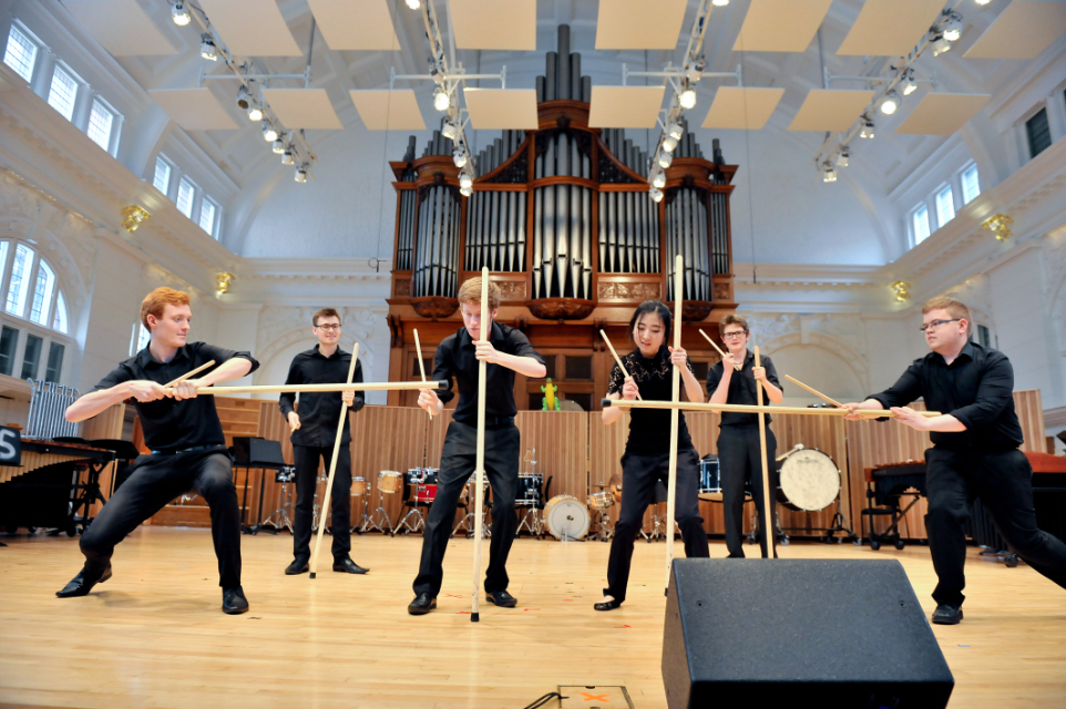 Six students with drum sticks performing at a Percussion Showcase, in the RCM's Amaryllis Fleming Concert Hall